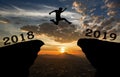 A young man jump between 2018 and 2019 years over the sun and through on the gap of hill silhouette