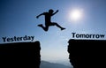 A young man jump between yesterday and tomorrow over the sun and through on the gap of hill silhouette evening colorful sky. Royalty Free Stock Photo