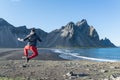 Young man jumping in the black sand beach of Stokksnes Peninsula. Iceland