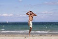 Young man jumping on the blue beach. Royalty Free Stock Photo