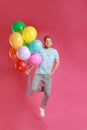 Young man jumping with bunch of colorful balloons on background Royalty Free Stock Photo