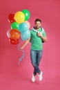 Young man jumping with bunch of colorful balloons Royalty Free Stock Photo