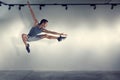 Young man jumping in front of gray wall Royalty Free Stock Photo