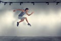 Young man jumping in front of gray wall Royalty Free Stock Photo