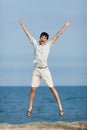 Young man jumping with hands raised against sea Royalty Free Stock Photo