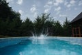 Young man jumping in swimming pool in the garden. healthy lifestyle. Huge splashing water Royalty Free Stock Photo