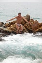 Young man jumping into water from pile of rocks Royalty Free Stock Photo