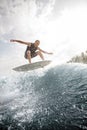 Young man jumping on the white wakeboard down the blue water against grey sky Royalty Free Stock Photo