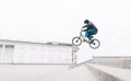 Young man jumps on the BMX from the stairs against the backdrop of a minimalistic urban landscape Royalty Free Stock Photo