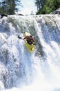 Young man kayaking down waterfall