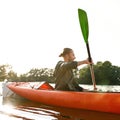 Young man kayaking on river, holding paddle, looking away on a summer day Royalty Free Stock Photo