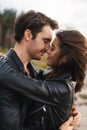 Man kissing brunette girlfriend in leather