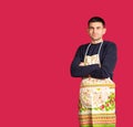 Young man in a kitchen apron on pink background with blank space. The concept of gender stereotypes