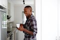 Young man in the kitchen with coffee using cell phone Royalty Free Stock Photo