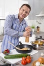 Young man in the kitchen cooking fried eggs. Royalty Free Stock Photo