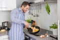 Young man in the kitchen cooking fried eggs. Royalty Free Stock Photo