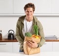 I take pride in what goes into my body. A young man in a kitchen holding a brown paper bag filled with vegetables. Royalty Free Stock Photo