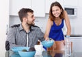 Young man at kitchen table and woman preparing breakfast Royalty Free Stock Photo