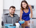 Young man at kitchen table and woman preparing breakfast Royalty Free Stock Photo