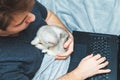 Young man with kitten working at his laptop Royalty Free Stock Photo