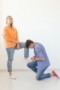 Young man is kneeling and reverently tying shoelaces to his domineering unidentified woman posing on a white background Royalty Free Stock Photo