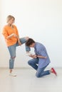 Young man is kneeling and reverently tying shoelaces to his domineering unidentified woman posing on a white background Royalty Free Stock Photo