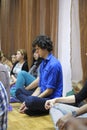 Young man Krishna follower sitting on a floor in a temple and praying meditating. Kyiv, Ukraine