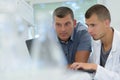 Young man on labcoat showing information to supervisor