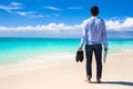 Young man with laptop on the background of turquoise ocean at tropical beach