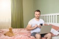 Cheerful young adult working from his apartment bed Royalty Free Stock Photo