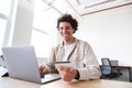 Young man with laptop at desk making business transaction with credit card in open plan office space