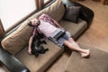 Young man with a laptop fell asleep on a soft sofa, next to him funny, belly up, lies his dog Schnauzer Royalty Free Stock Photo