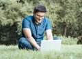 Young man with laptop outdoor sitting on the grass Royalty Free Stock Photo