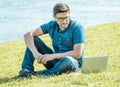 Young man with laptop outdoor sitting on the grass Royalty Free Stock Photo