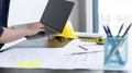 Young man with a laptop plotting a system of building structures in blueprints