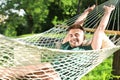 Young man with laptop resting in comfortable hammock at garden