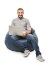 Young man with laptop sitting on beanbag chair against white background Royalty Free Stock Photo