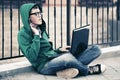 Young man with laptop sitting on sidewalk Royalty Free Stock Photo