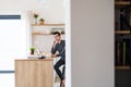 Young man with laptop and smartphone sitting in kitchen, a home office concept. Royalty Free Stock Photo