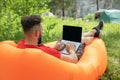 young man with laptop working outdoor. Freedom, remote work, freelancer, technology, internet, travel, vacation concepts