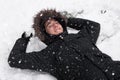 Young man laughing, with happy expression, snow covered, lying on the ground in snowfall. Royalty Free Stock Photo