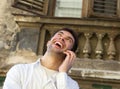 Young man laughing outdoors with mobile phone Royalty Free Stock Photo