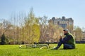 Young man on the lawn with a bicycle. He holds a glass of coffee in his hand