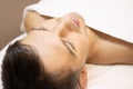 Young man laying on a facial therapy couch covered with the white towel with closed eyes.