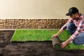 Young man laying grass sod on ground at backyard Royalty Free Stock Photo