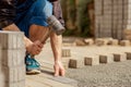 Young man laying gray concrete paving slabs in house courtyard on gravel foundation base. Master lays paving stones