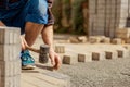 Young man laying gray concrete paving slabs in house courtyard on gravel foundation base. Master lays paving stones