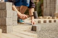 Young man laying gray concrete paving slabs in house courtyard on gravel foundation base. Master lays paving stones