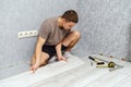 Young man is laying wooden panel of laminate floor