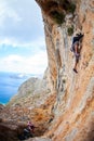 Young man lead climbing on cliff near sea